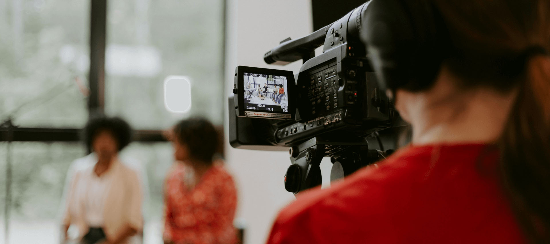 Kamera filmt zwei Personen im Interview, im Vordergrund eine Person mit Kopfhörer beim Filmen
